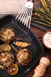 Photo of Tasty grilled artichokes on wooden table, flat lay