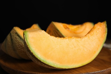 Photo of Tasty fresh cut melon on wooden tray, closeup