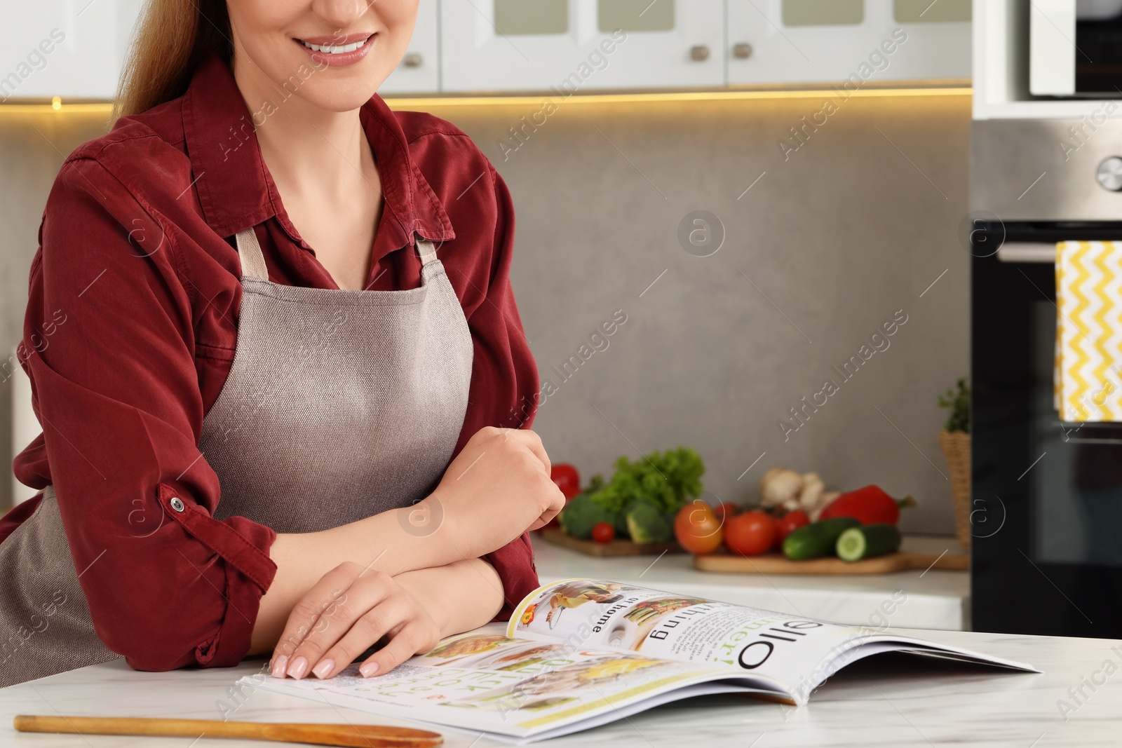 Photo of Woman reading recipe in culinary magazine at home, closeup. Space for text