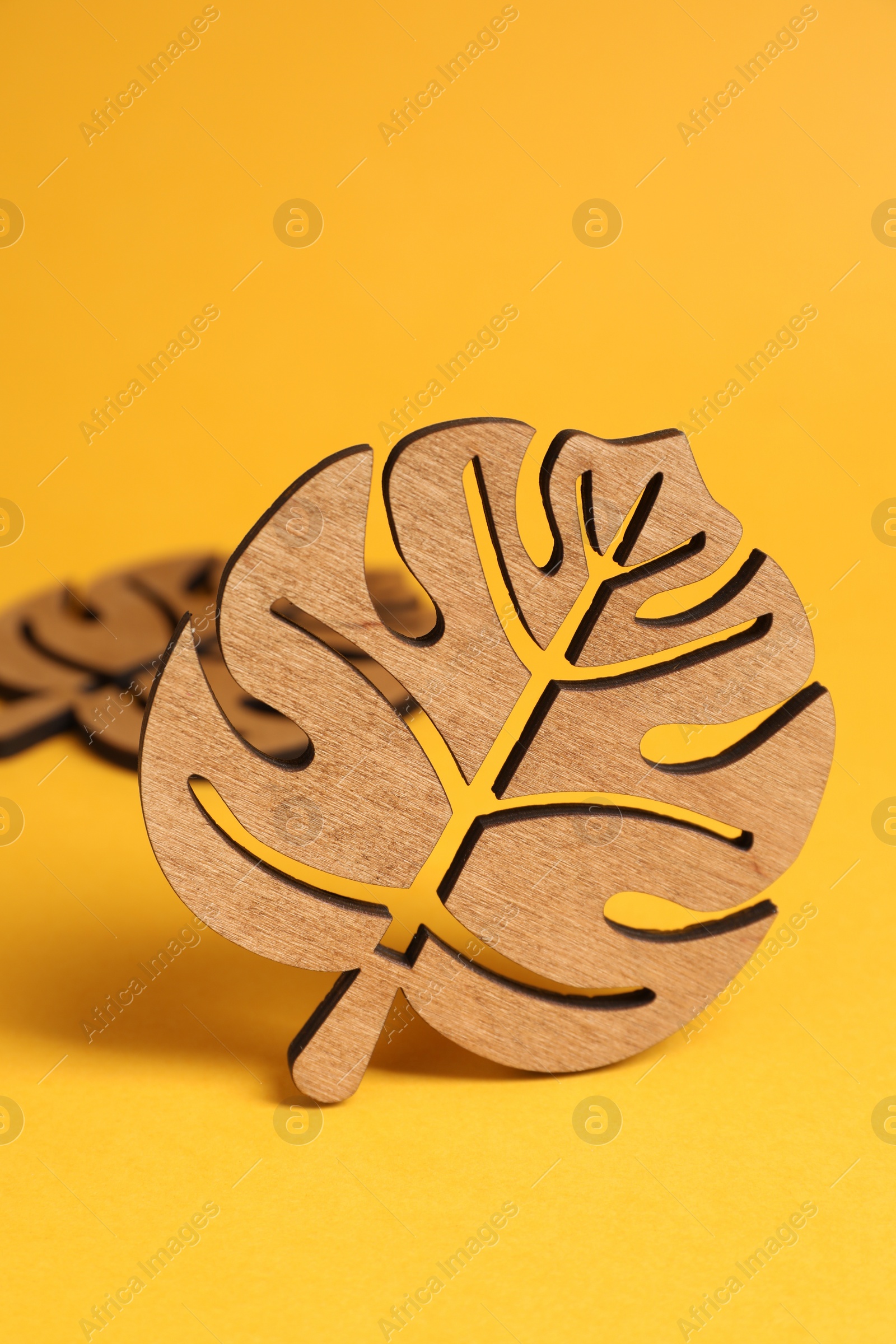 Photo of Leaf shaped wooden cup coasters on yellow background