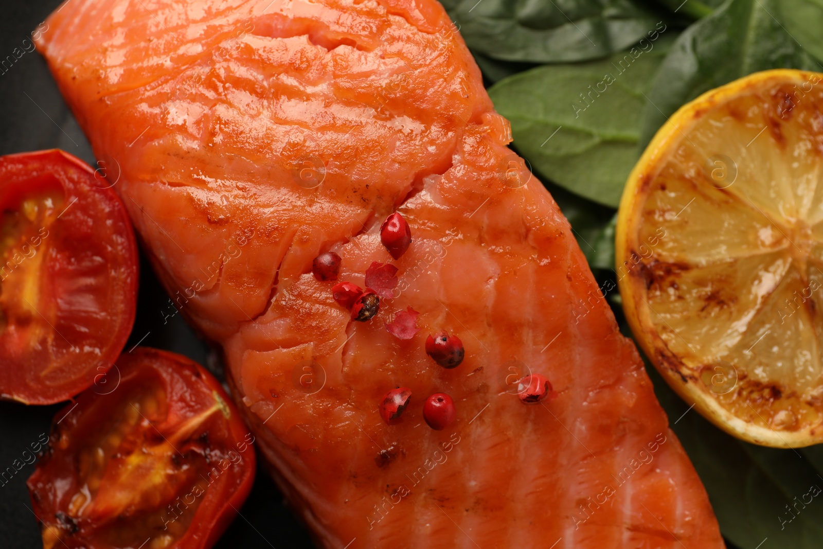 Photo of Plate with tasty grilled salmon, tomatoes, lemon and basil, top view