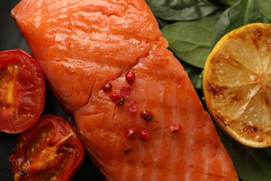 Plate with tasty grilled salmon, tomatoes, lemon and basil, top view