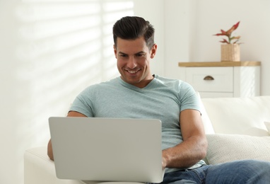 Man using laptop for search on sofa at home