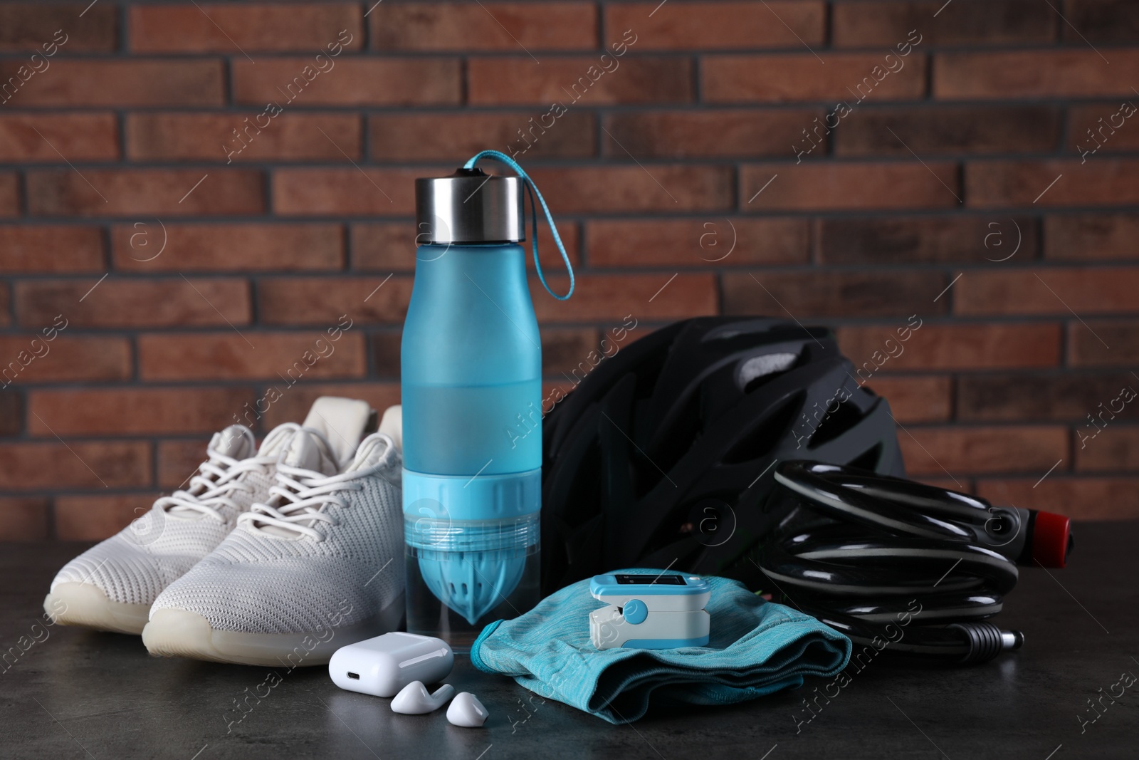 Photo of Different cycling accessories on black table against brick wall