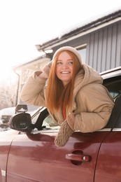 Happy young woman looking out of car window. Winter vacation