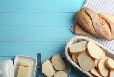 Photo of Tasty fresh bread with butter on light blue wooden table, flat lay. Space for text