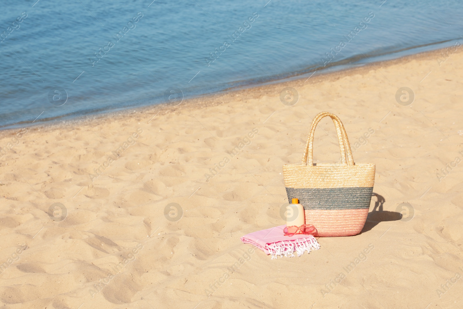 Photo of Stylish beach accessories on sand near sea. Space for text
