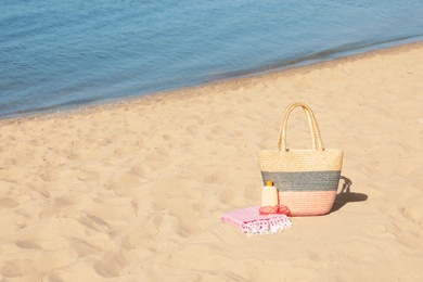 Photo of Stylish beach accessories on sand near sea. Space for text