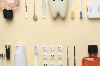 Photo of Plastic teeth with cute faces, oral care products and dental tools on beige background, flat lay. Space for text