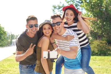 Group of young people taking selfie with monopod outdoors