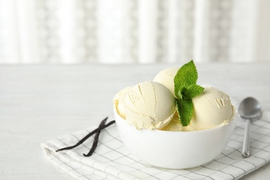 Photo of Delicious vanilla ice cream with mint in bowl served on table. Space for text