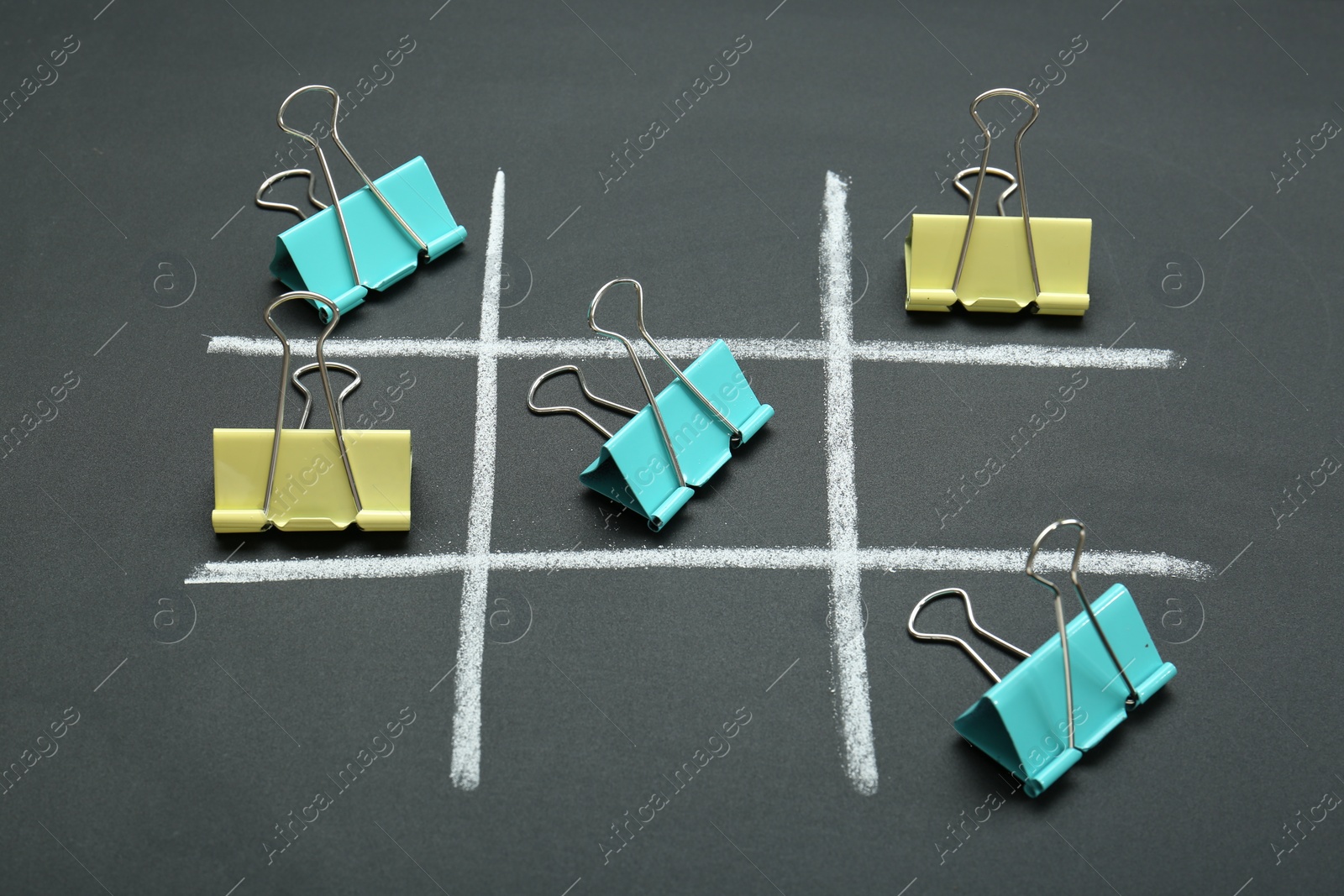 Photo of Tic tac toe game made with paper clips on chalkboard