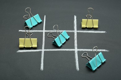 Photo of Tic tac toe game made with paper clips on chalkboard