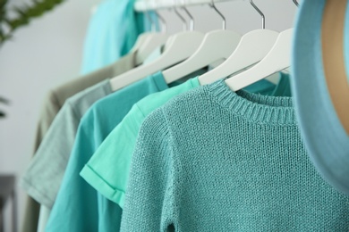 Photo of Hangers with mint clothes on rack, closeup