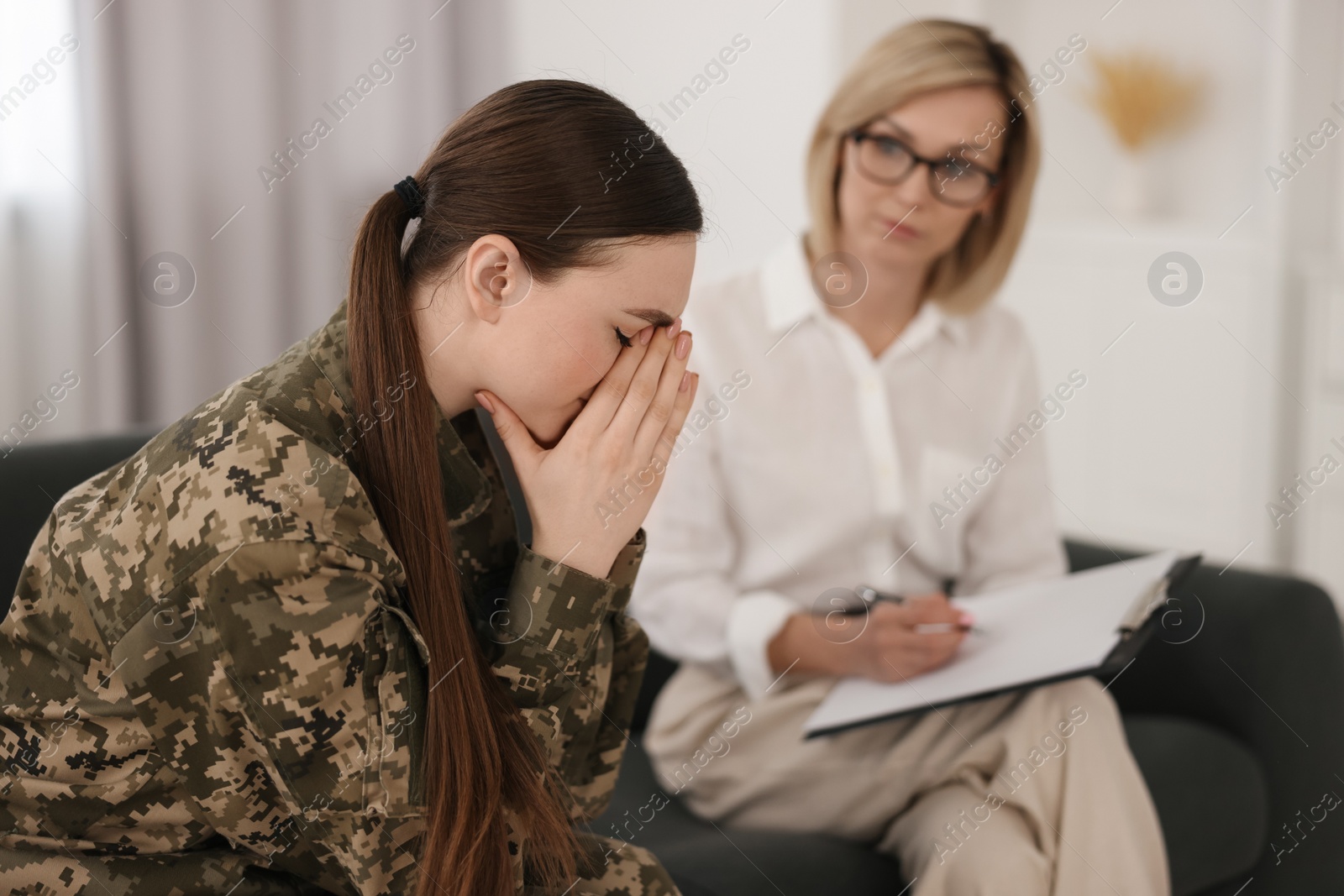 Photo of Psychotherapist working with military woman on sofa in office