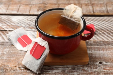 Photo of Tea bags and cup of aromatic drink on wooden rustic table, closeup