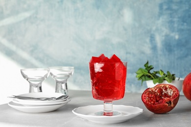 Photo of Composition with glass of pomegranate jelly on table against color background. Space for text