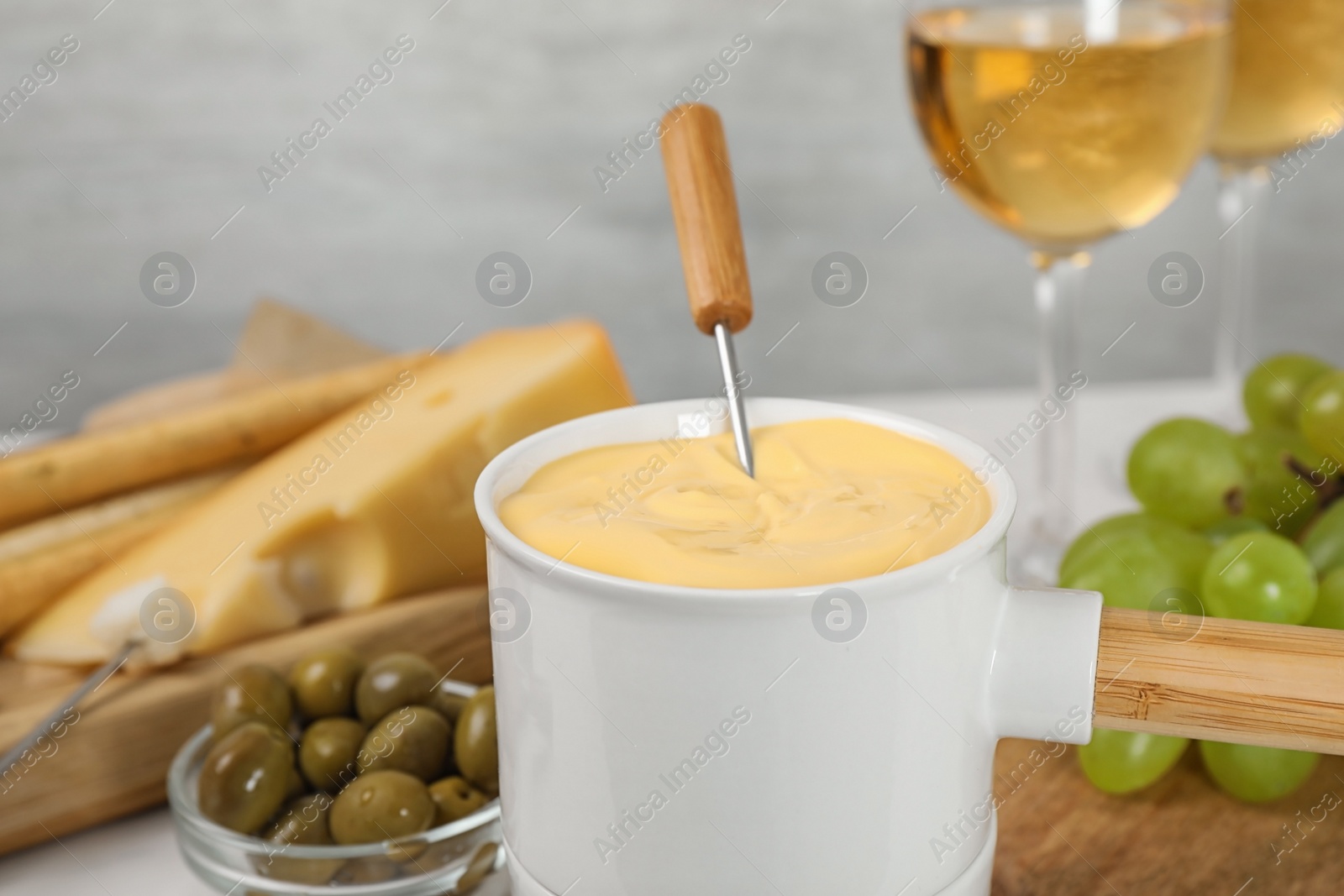 Photo of Pot of tasty cheese fondue and products on table