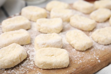 Making lazy dumplings. Cut dough and flour on wooden board, closeup