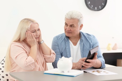 Mature couple thinking over pension payment at home