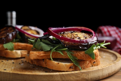 Photo of Delicious eggplant sandwiches served on wooden board, closeup