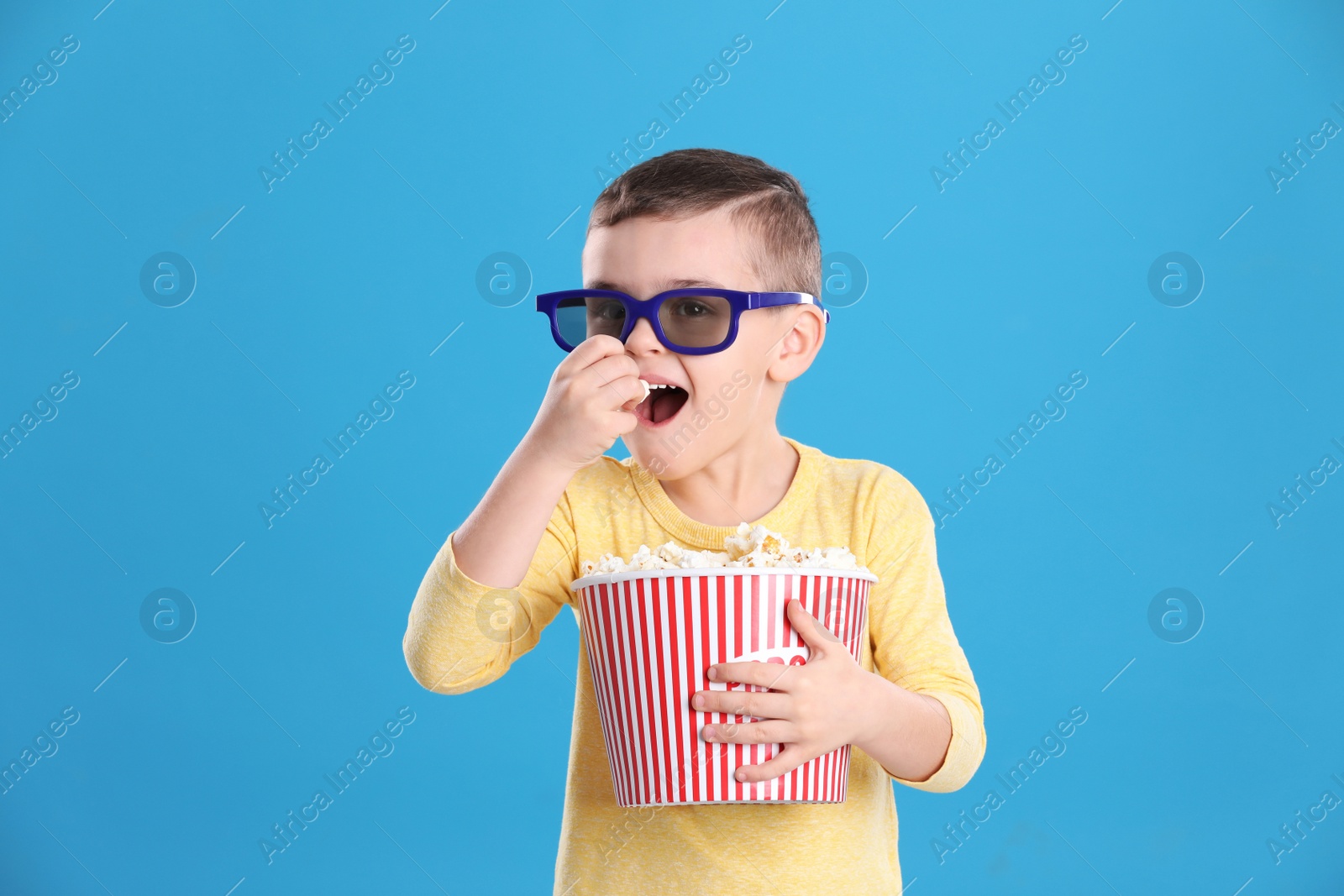 Photo of Cute little boy with popcorn and glasses on color background