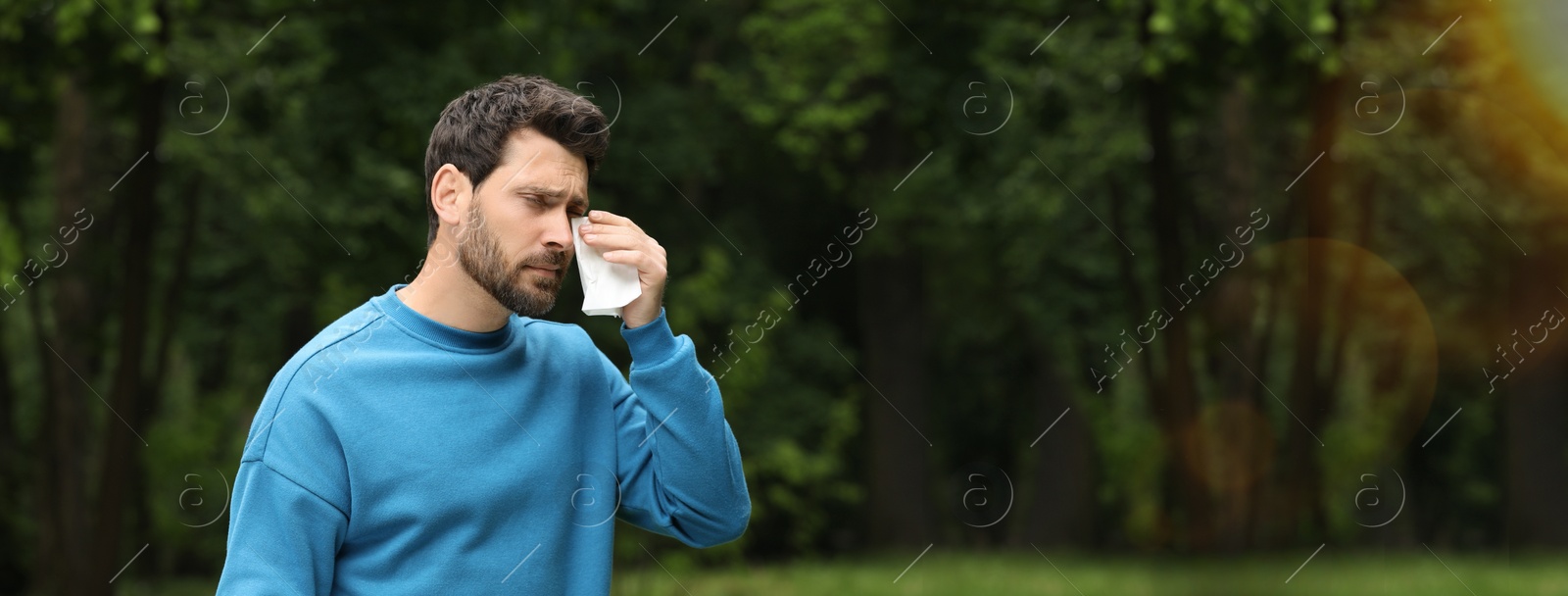 Image of Man suffering from seasonal spring allergy outdoors. Banner design with space for text