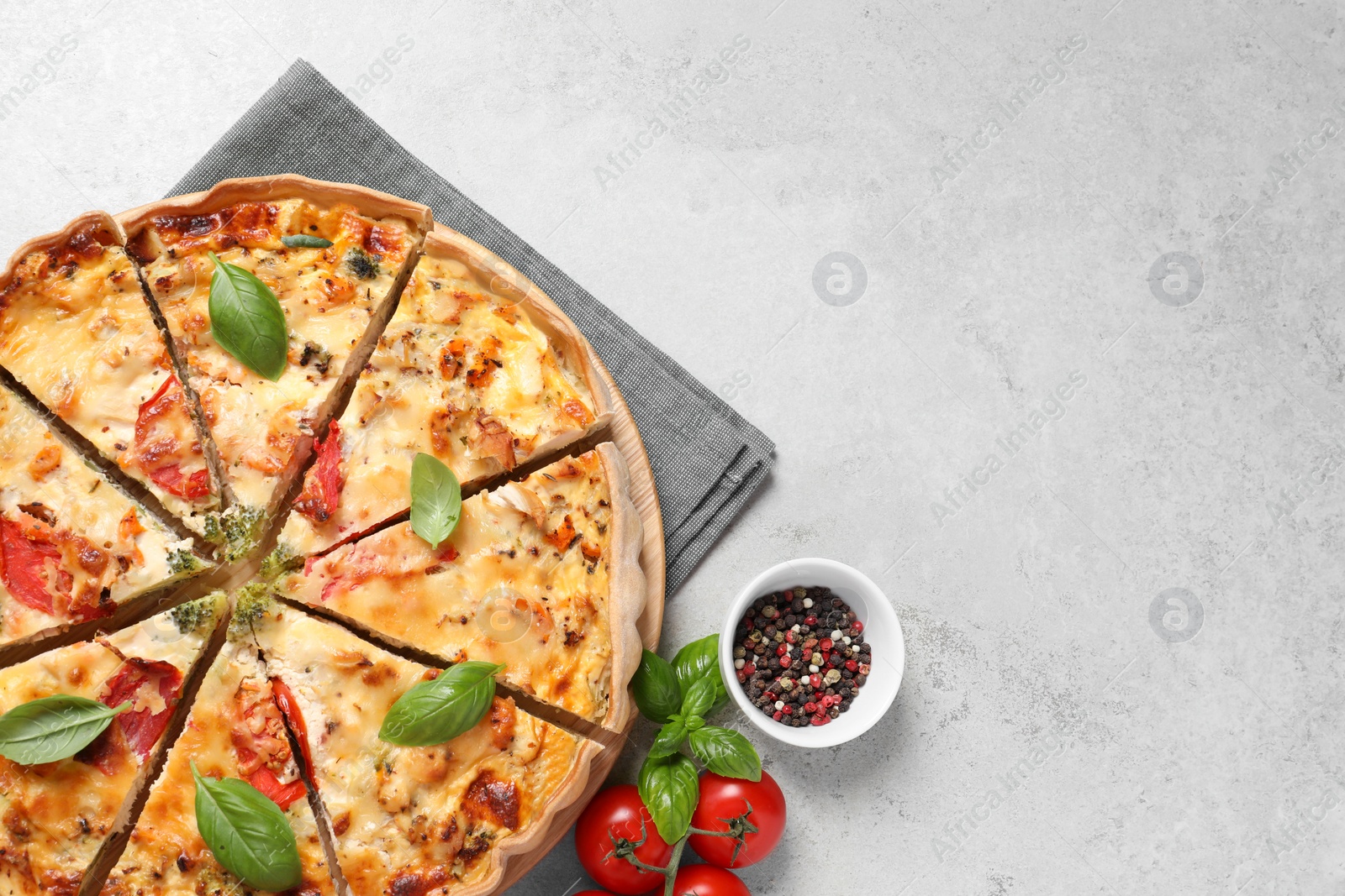 Photo of Tasty quiche with tomatoes, basil and cheese served on light textured table, flat lay. Space for text