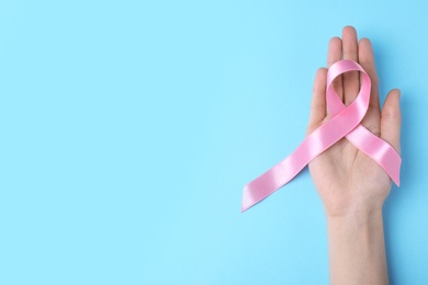 Photo of Woman with symbolic ribbon of breast cancer awareness and space for text on color background, top view. Gynecological care