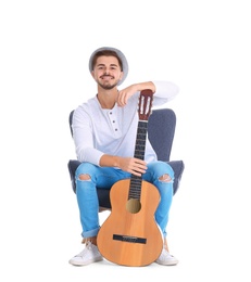 Handsome young man with guitar in armchair on white background