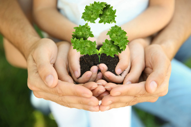 Family holding fertile soil in hands on blurred background and recycling symbol, closeup