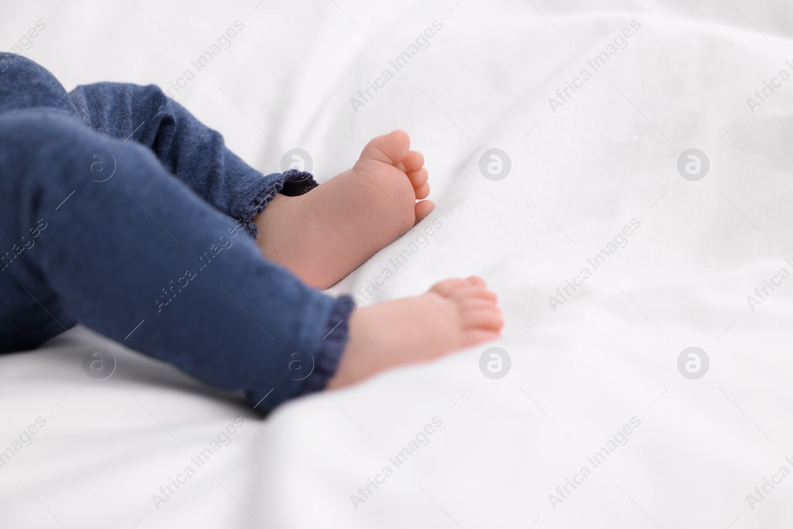 Photo of Newborn baby lying on white blanket, closeup. Space for text