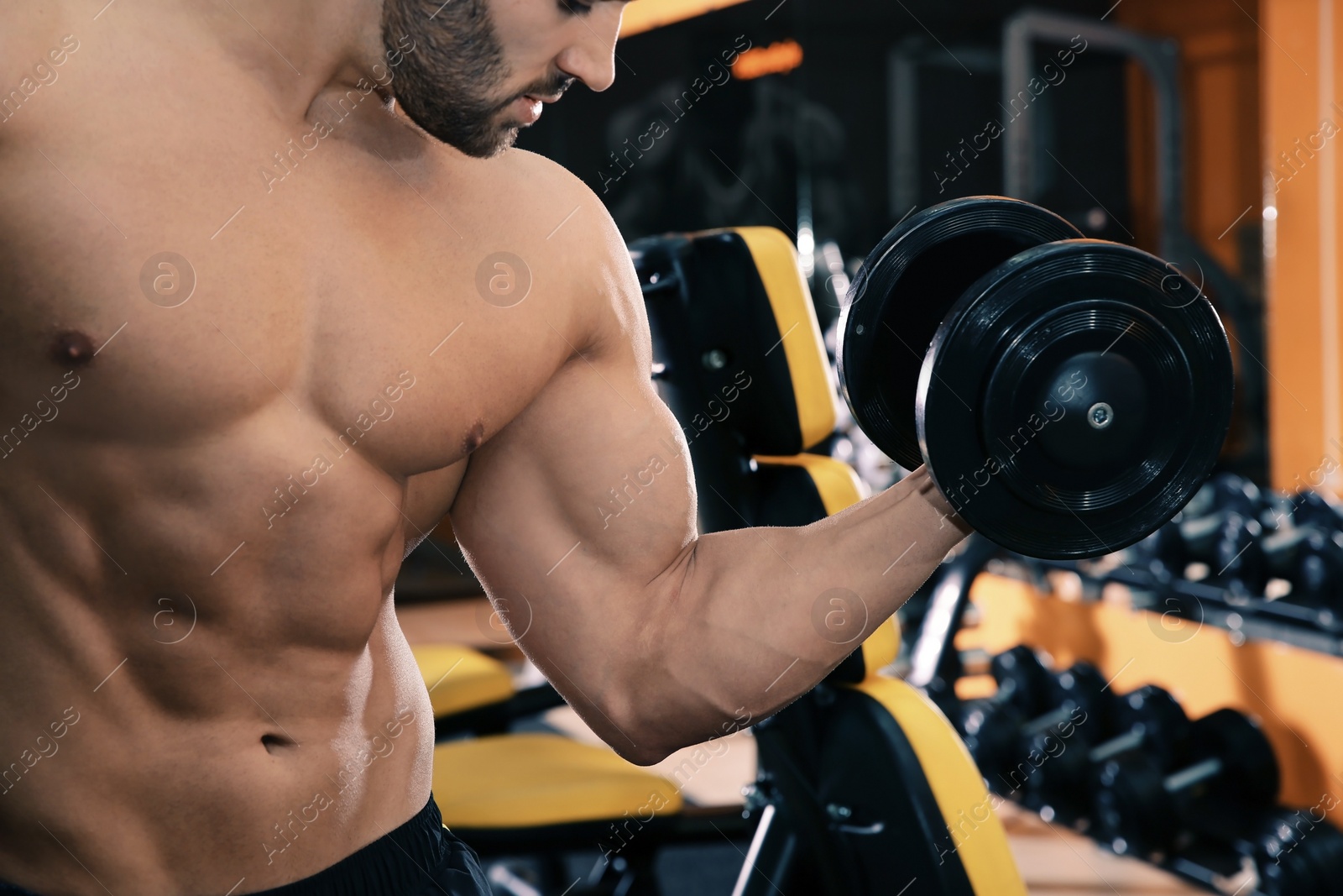 Photo of Strong young man lifting dumbbell in gym