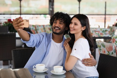 Photo of International dating. Happy couple taking selfie in restaurant