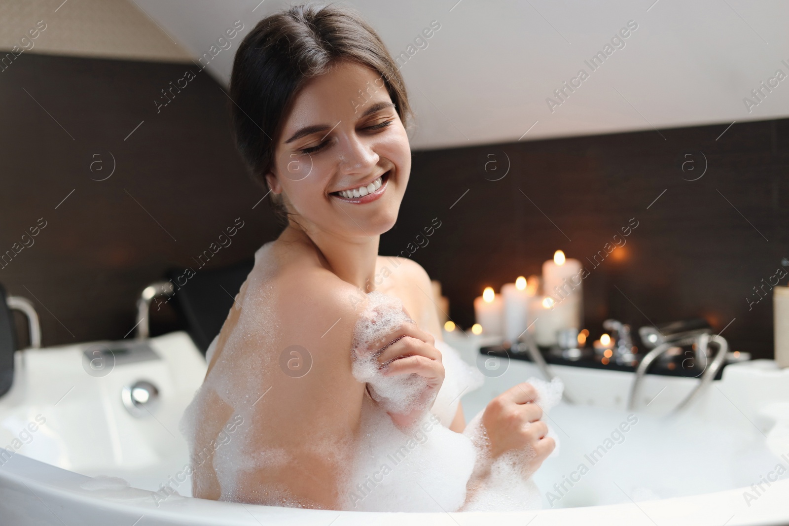 Photo of Happy beautiful woman taking bubble bath. Romantic atmosphere