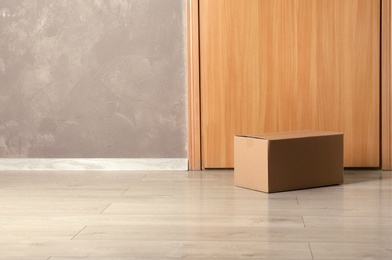 Cardboard box on floor near apartment entrance. Mockup for design