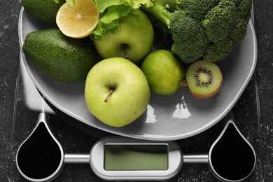 Photo of Healthy diet. Scale and fresh products on black textured table, top view