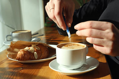 Photo of Woman with cup of fresh aromatic coffee at table in cafe