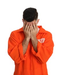 Remorseful prisoner in orange jumpsuit hiding his face on white background