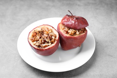 Photo of Tasty baked apples with nuts and honey on gray table