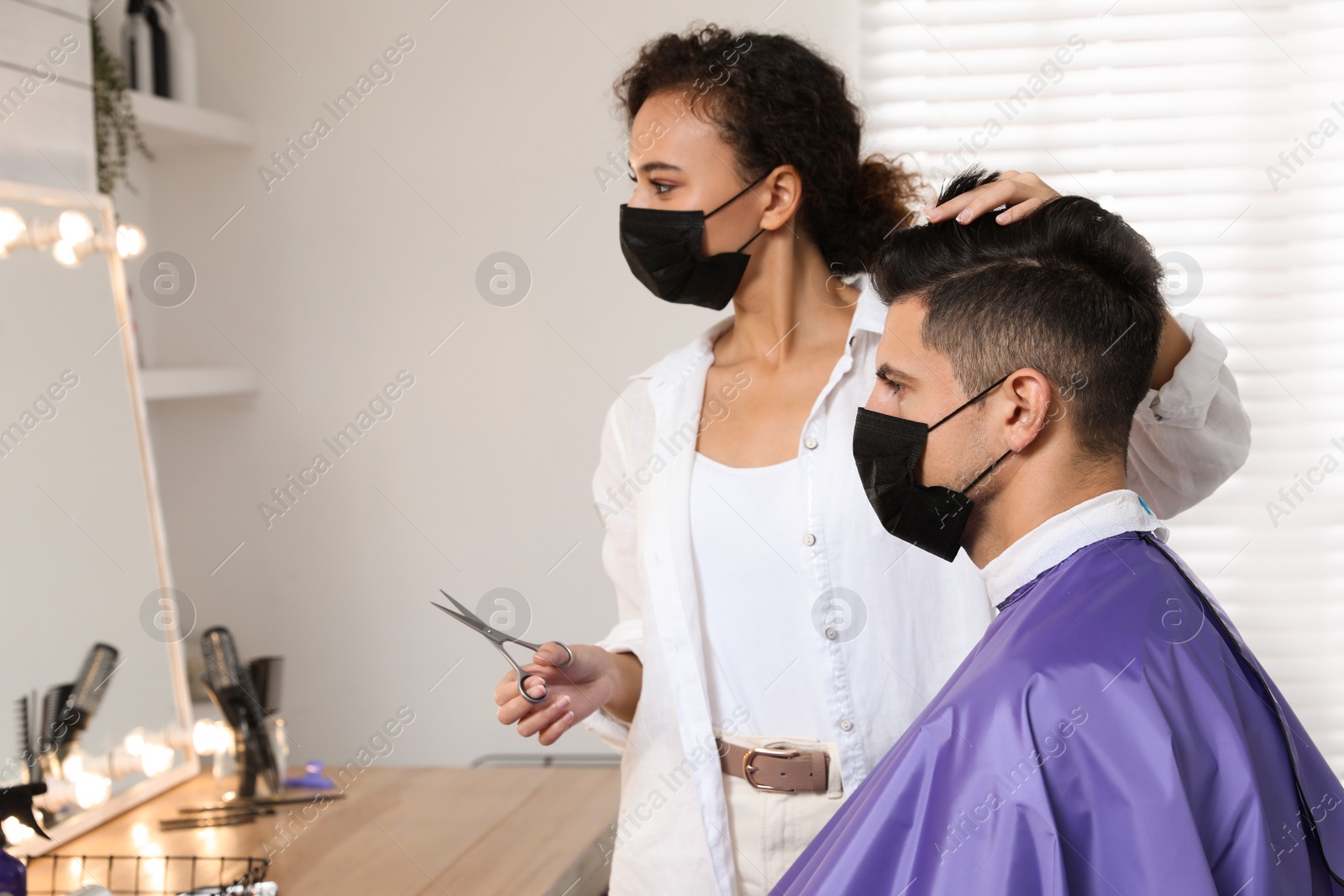 Photo of Professional stylist working with client in salon. Hairdressing services during Coronavirus quarantine