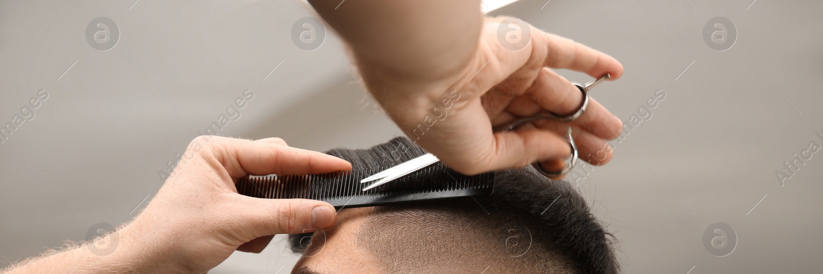 Image of Professional barber making stylish haircut in salon, closeup. Banner design