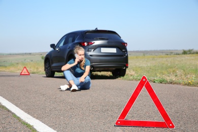 Photo of Emergency stop sign and woman near broken car on background