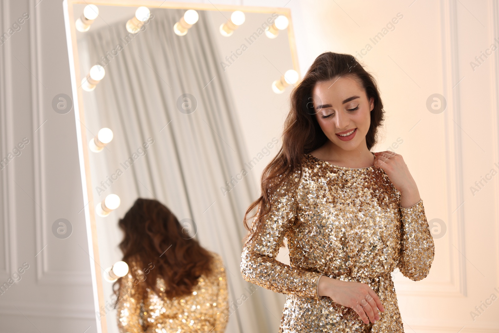 Photo of Beautiful woman in elegant dress near mirror indoors, space for text
