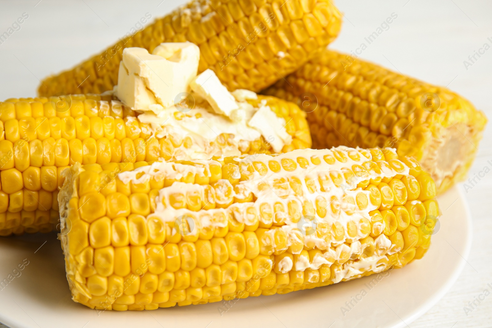 Photo of Delicious boiled corn with butter on plate, closeup