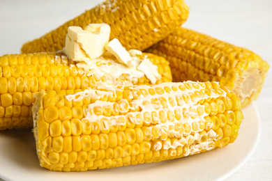 Photo of Delicious boiled corn with butter on plate, closeup
