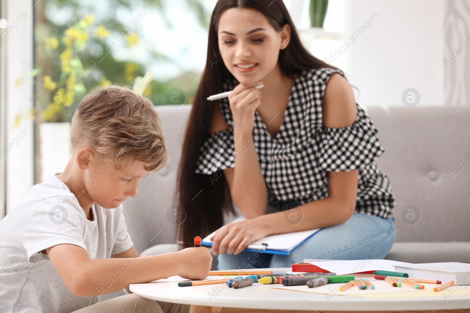 Photo of Young female psychologist working with little child in office