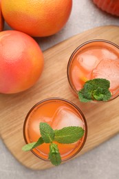 Photo of Tasty freshly made grapefruit juice, fruits and mint on light grey table, top view