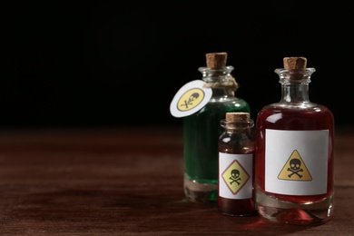 Photo of Bottles with poisons on wooden table. Space for text