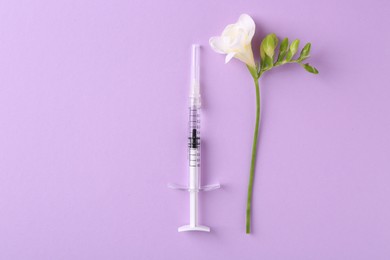 Photo of Cosmetology. Medical syringe and freesia flower on violet background, top view. Space for text